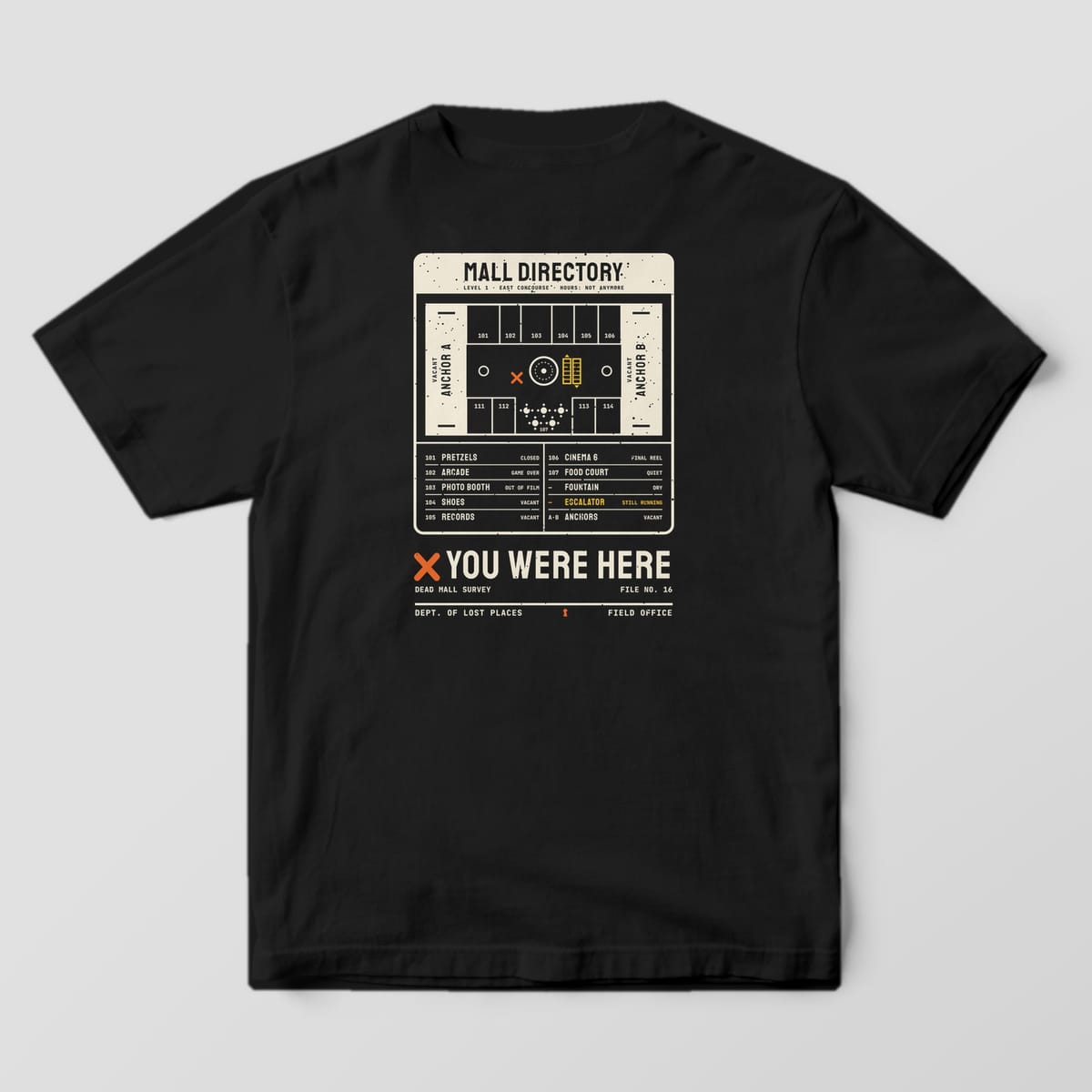 Back of a Black Comfort Colors 1717 tee printed with a cream mall directory board with a floor map, vacant anchor stores, a yellow escalator and a store list, above an orange X and the words You Were Here.