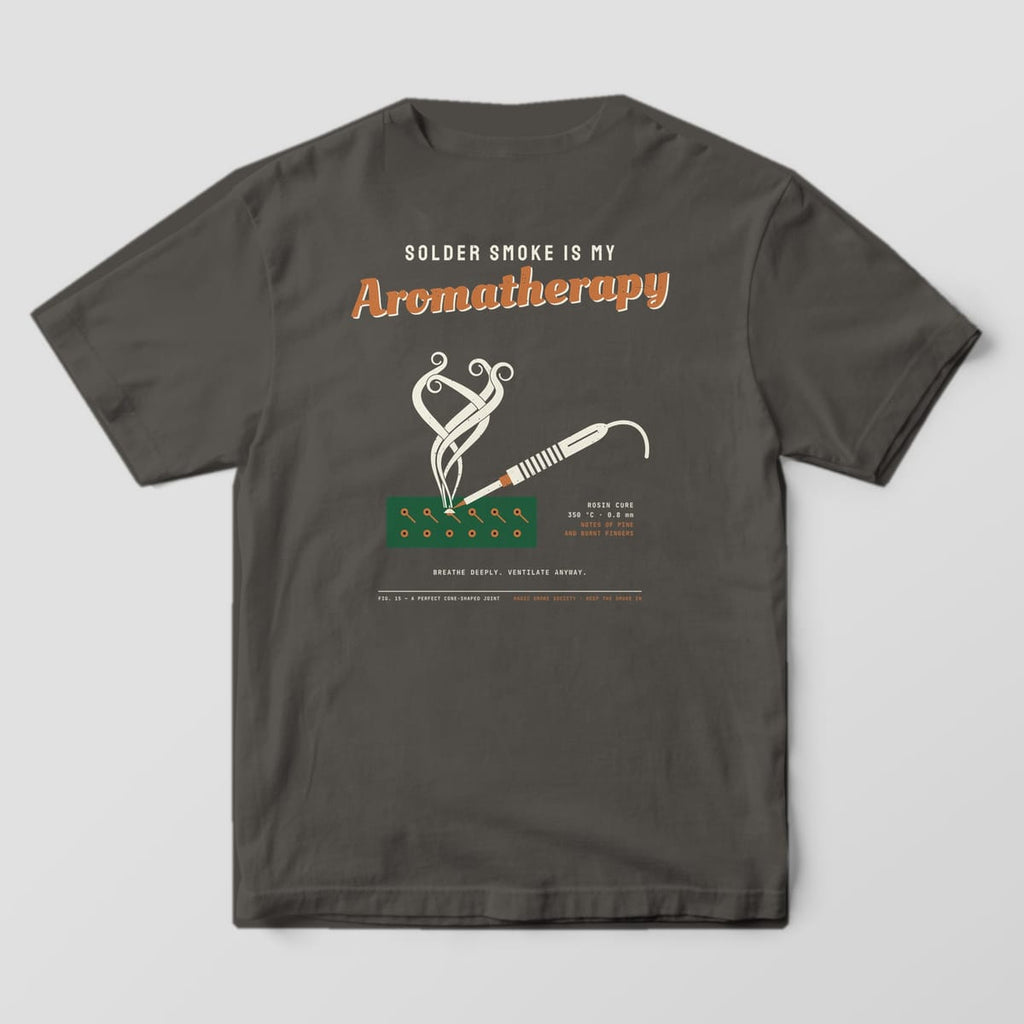 Back of a pepper Comfort Colors 1717 tee with a Solder Smoke Is My Aromatherapy print in cream, copper and green.