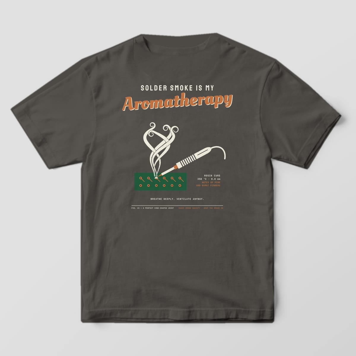 Back of a pepper Comfort Colors 1717 tee with a Solder Smoke Is My Aromatherapy print in cream, copper and green.