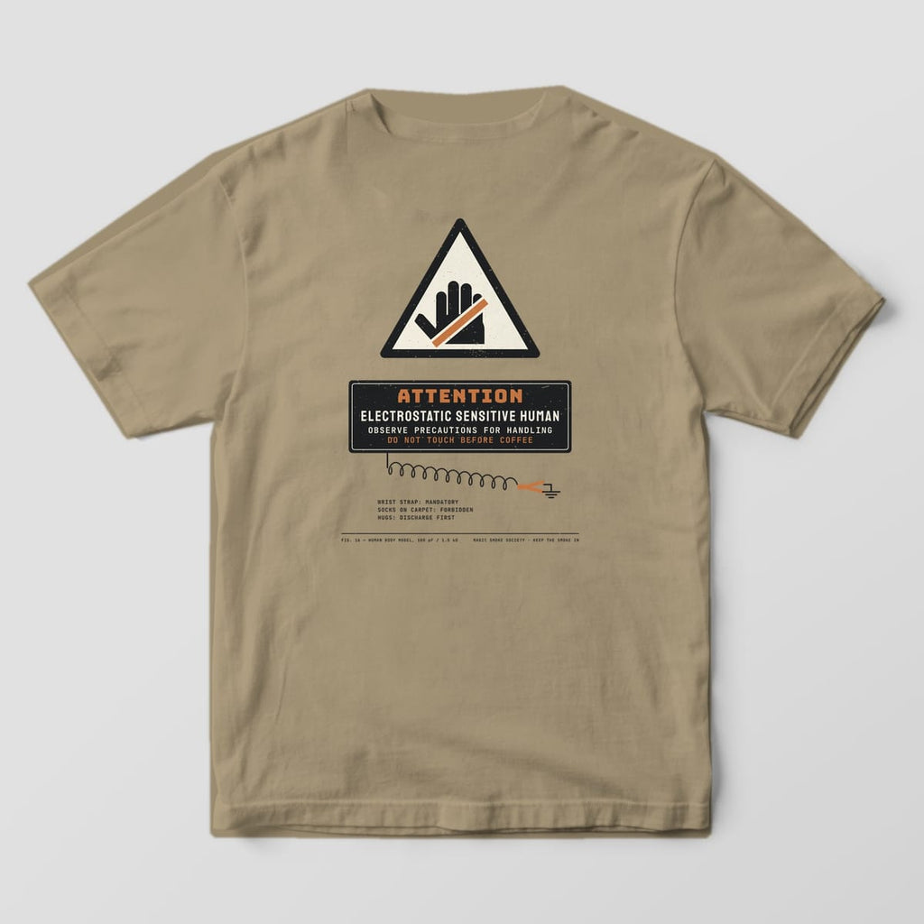 Back of a khaki Comfort Colors 1717 tee with an ESD Sensitive Human warning label print and a coiled wrist strap.