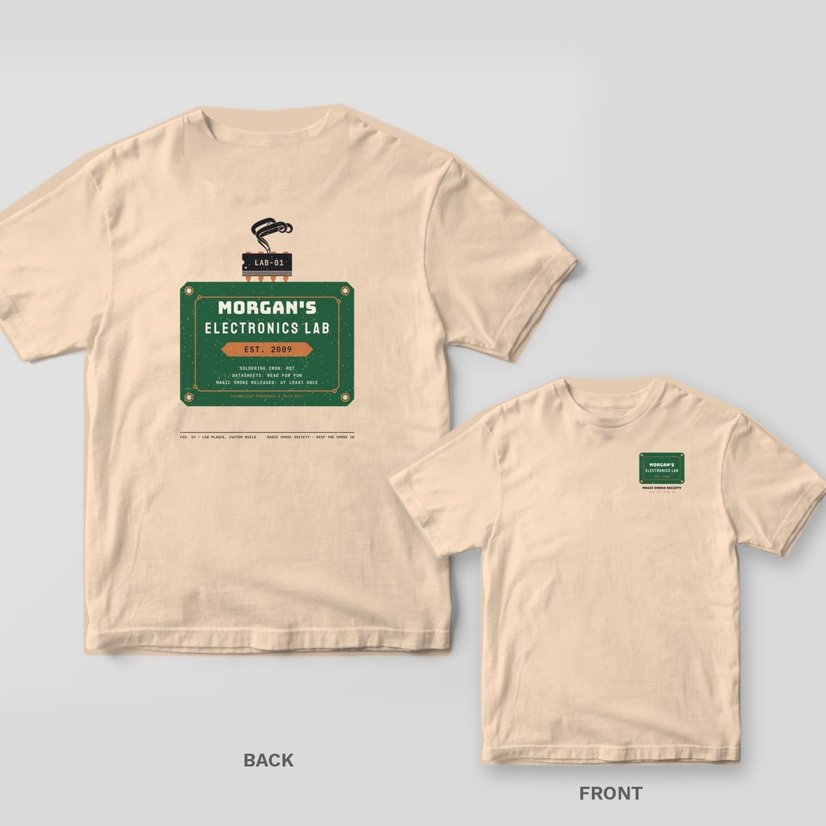 Ivory tee shown back and front: back has a green circuit-board plaque reading Morgan's Electronics Lab Est. 2009 with a smoking chip on top; front has a small plaque.