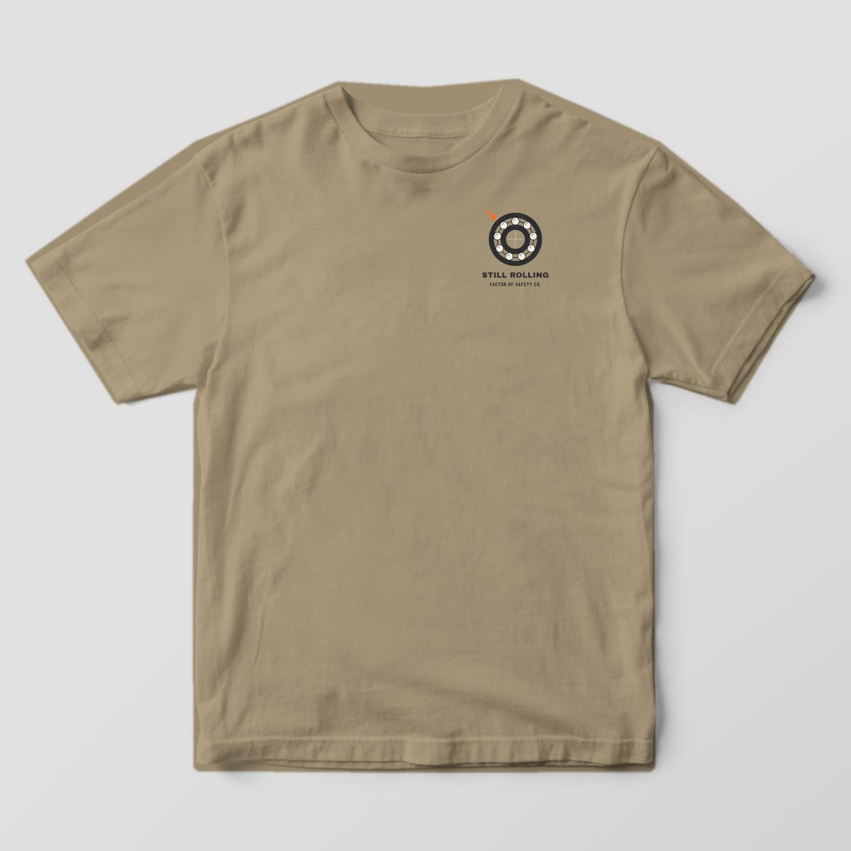 Front of a khaki Comfort Colors 1717 tee with a small ball bearing on the left chest.