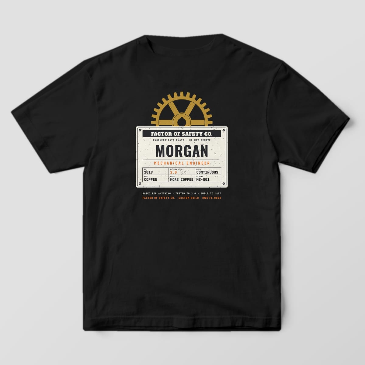 Back of a black Comfort Colors 1717 tee with the large Custom Mechanical Engineer print: a cream riveted data plate with a personalized name under a brass gear.