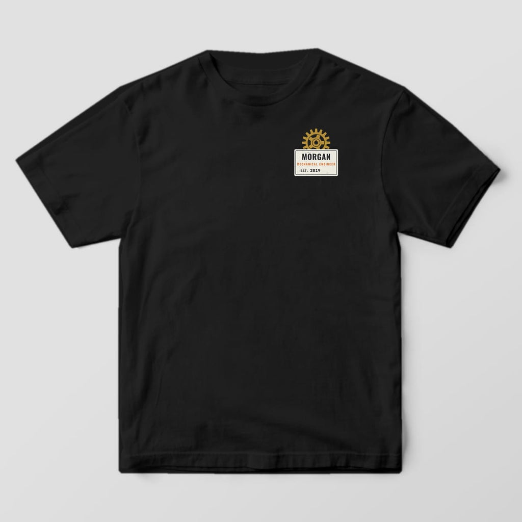 Front of a black Comfort Colors 1717 tee with a small personalized data plate with a brass gear on the left chest.