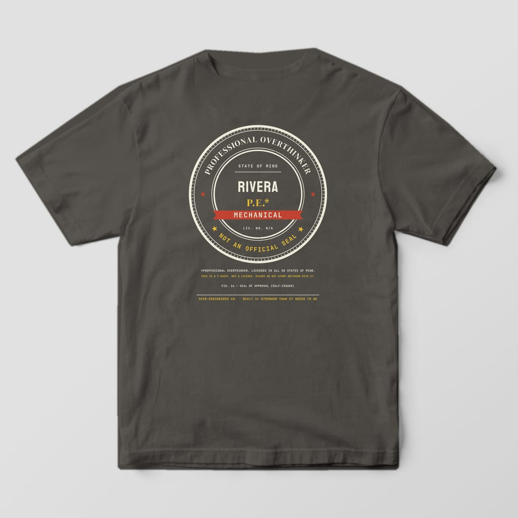 Back of a pepper Comfort Colors 1717 tee with a large round Professional Overthinker seal with the sample name RIVERA and MECHANICAL.
