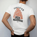 Man wearing a White tee, seen from the back: a tall wall of stacked shoeboxes with tissue paper peeking out, Certified stamped above and Box Hoarder below, as a two-ink streetwear graphic in off-white and orange.