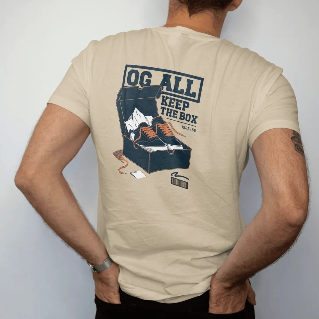 Man wearing a Sandstone tee, seen from the back: an open shoebox with tissue paper, spare laces and a hangtag under an OG All banner and Keep The Box script, as a two-ink streetwear graphic in navy and orange.