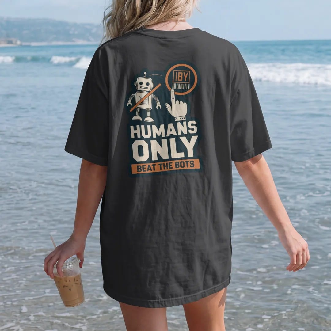 Woman on the beach in a Black tee, back view: a crossed-out cartoon robot beside a hand clicking a buy button, labeled Humans Only and Beat The Bots, as a two-ink streetwear graphic in off-white and orange.