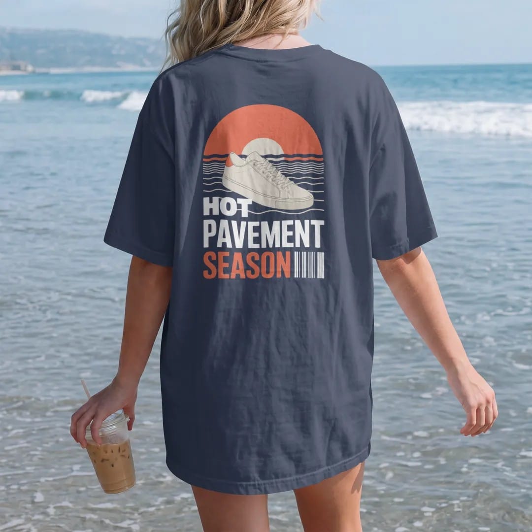 Woman on the beach in a Navy tee, back view: a sneaker on sizzling asphalt with heat waves and a big sun, under wavy Hot Pavement and Season, as a two-ink streetwear graphic in off-white and orange.