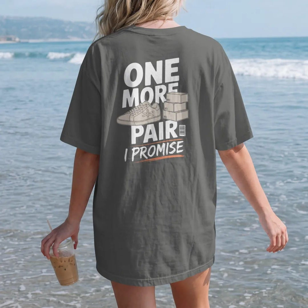 Woman on the beach in a Pepper tee, back view: a sneaker with crossed fingers beside a stack of delivery boxes, labeled One More Pair and a scrawled I Promise, as a two-ink streetwear graphic in off-white and orange.
