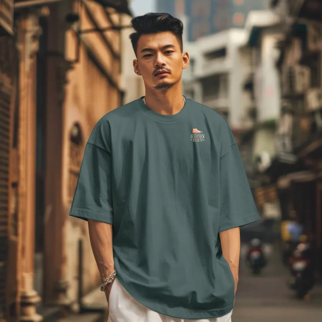 Man in a Blue Spruce tee on a city street, with the small Deadstock Society logo on the left chest.