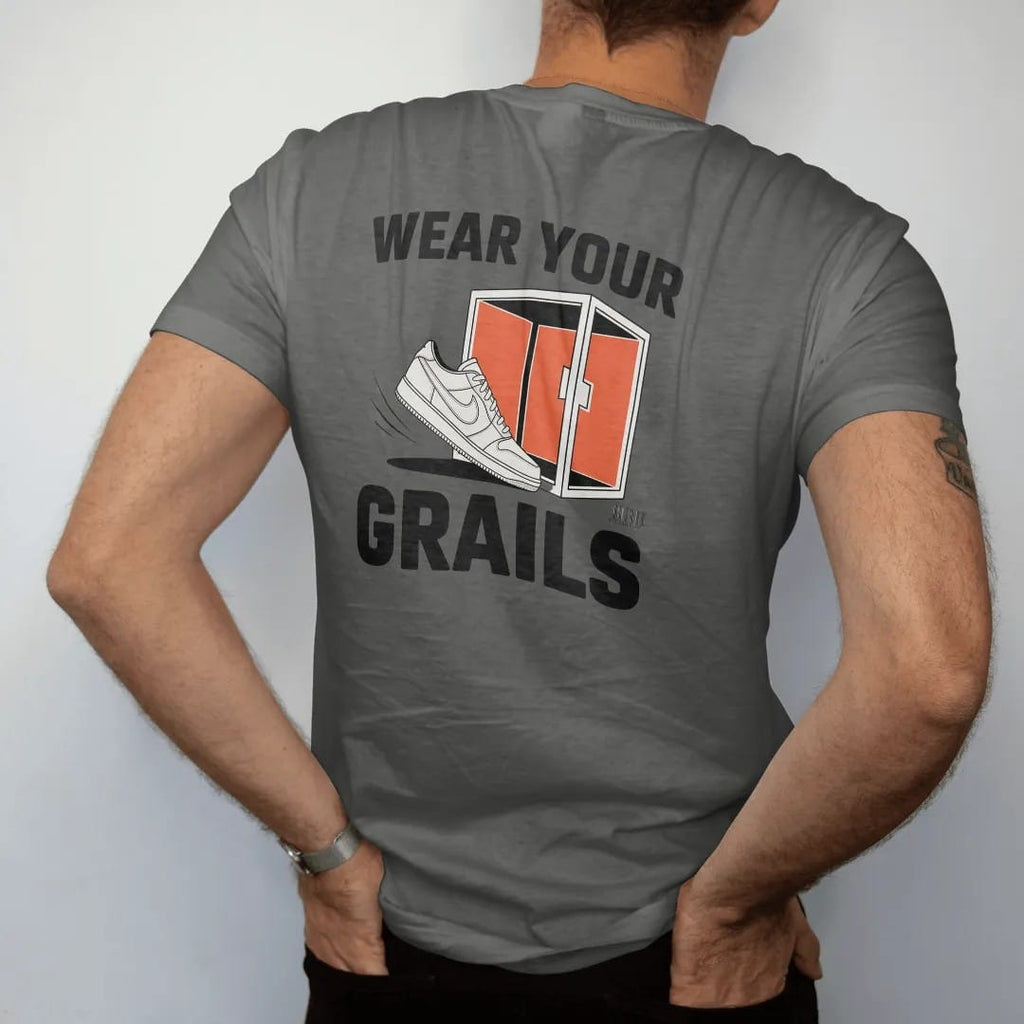 Man wearing a Pepper tee, seen from the back: a sneaker stepping out of an open glass display case under Wear Your and a huge Grails, as a two-ink streetwear graphic in off-white and orange.