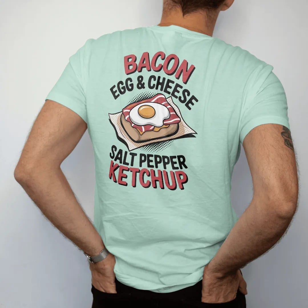 Man wearing a Chalky Mint tee, seen from the back: a bacon egg and cheese on a roll in deli paper with Bacon Egg & Cheese stacked above Salt Pepper Ketchup, in halftone comic-pop red, mustard and navy.