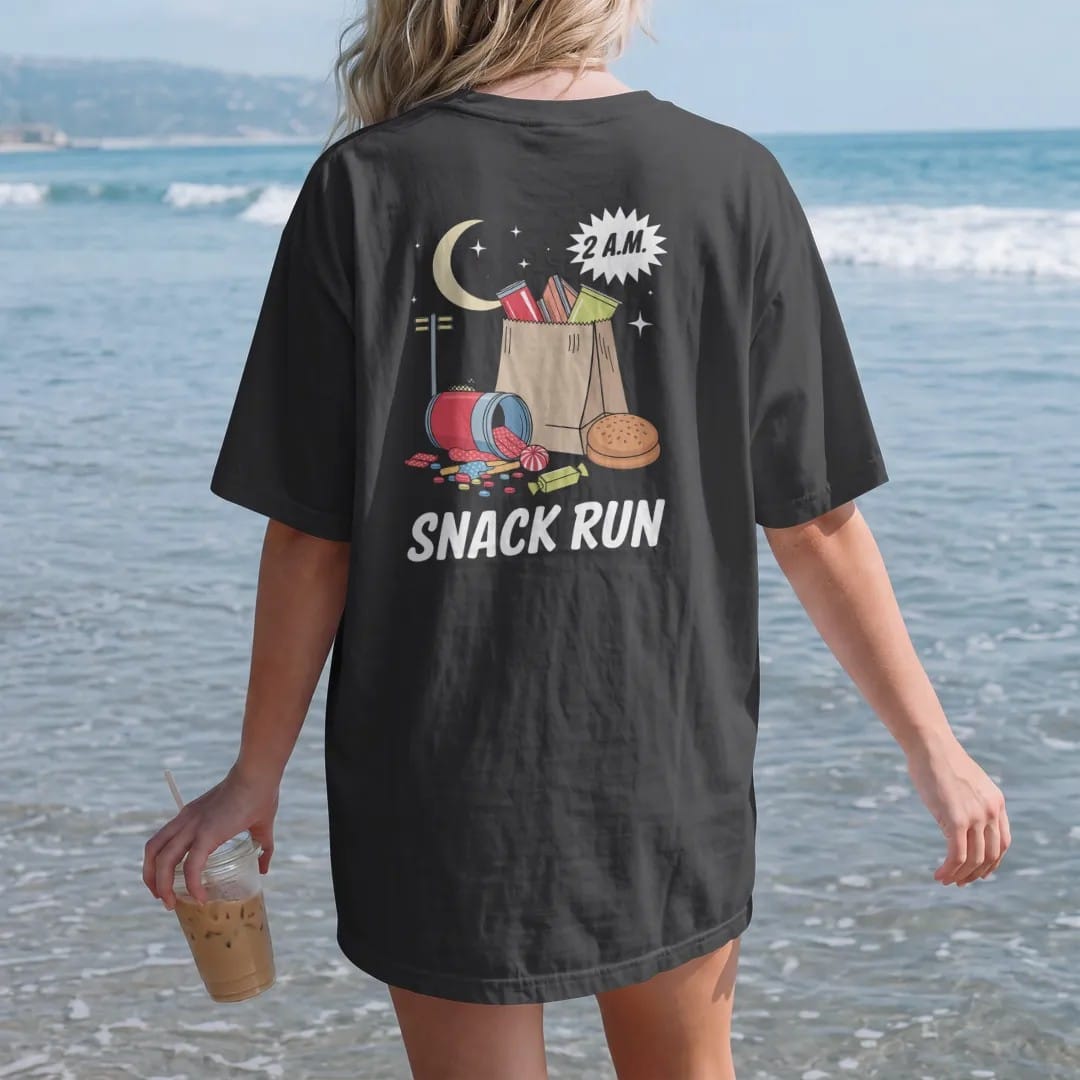 Woman on the beach in a Black tee, back view: a paper bag spilling chips, soda, candy and a honey bun under a crescent moon and streetlight, with 2 A.M. and Snack Run, in halftone comic-pop red, yellow and cream.