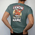 Man wearing a Blue Spruce tee, seen from the back: an orange cat with a name tag on a stack of newspapers with a heart, framed by I Know and The Cat's Name, in halftone comic-pop red, yellow and cream.
