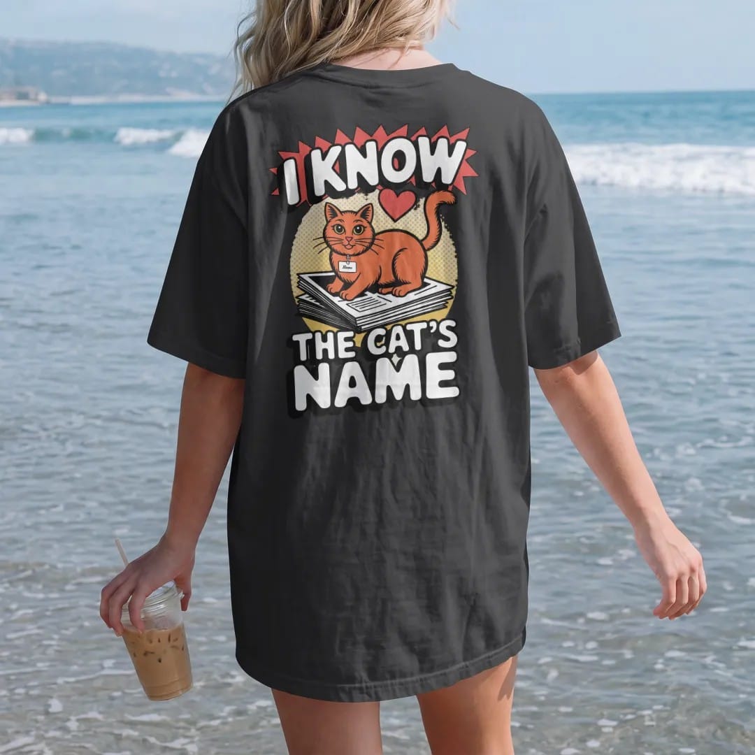Woman on the beach in a Black tee, back view: an orange cat with a name tag on a stack of newspapers with a heart, framed by I Know and The Cat's Name, in halftone comic-pop red, yellow and cream.