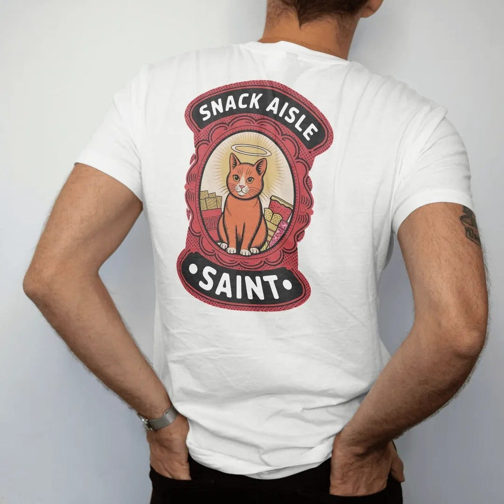 Man wearing a White tee, seen from the back: a prayer-candle label of a haloed orange cat surrounded by chips and candy, titled Snack Aisle Saint, in halftone comic-pop red, yellow and cream.