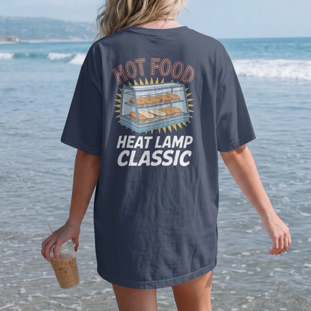 Woman on the beach in a Navy tee, back view: a glass warmer case under glowing heat lamps with foil-wrapped food, under neon Hot Food and Heat Lamp Classic, in halftone comic-pop red, yellow and cream.