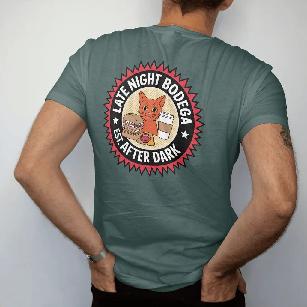 Man wearing a Blue Spruce tee, seen from the back: a round badge with an orange cat flanked by a sandwich and coffee cup, ringed by Late Night Bodega and Est. After Dark, in halftone comic-pop red, yellow and cream.
