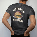 Man wearing a Black tee, seen from the back: a golden beef patty in coco bread with cheese and steam on deli paper, under Beef Patty and With Cheese, in halftone comic-pop red, yellow and cream.