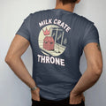 Man wearing a Midnight tee, seen from the back: a milk crate on the sidewalk with a floating crown and a cat beside it under Milk Crate and Throne, in halftone comic-pop red, yellow and cream.
