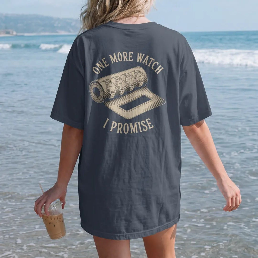 Woman on the beach in a Midnight tee, back view: an unrolled watch roll holding five watches and one glowing empty slot, under One More Watch and a scrawled I Promise, as a fine engraving in antique gold and cream.