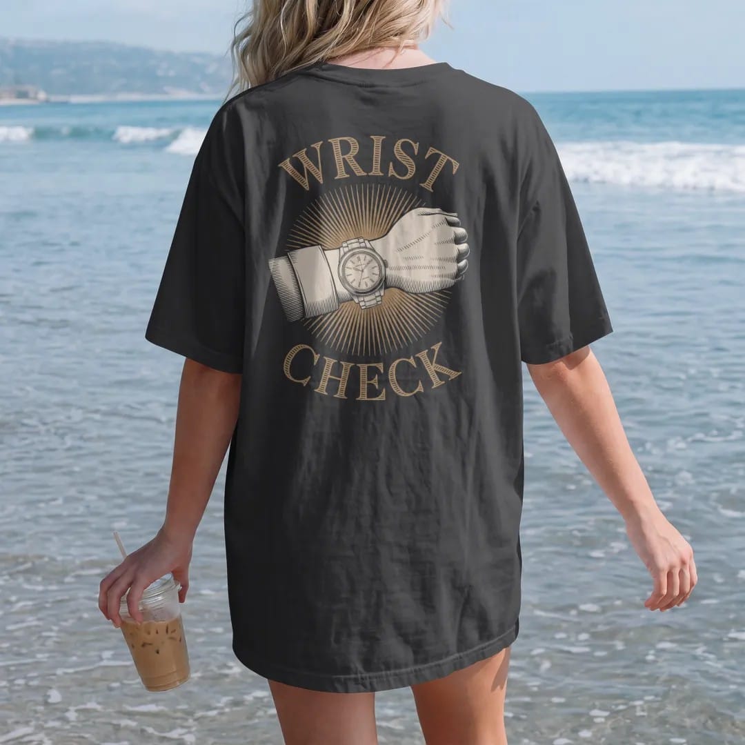 Woman on the beach in a Black tee, back view: a forearm wearing a steel wristwatch with camera-flash starburst lines under bold Wrist Check, as a fine engraving in antique gold and cream.