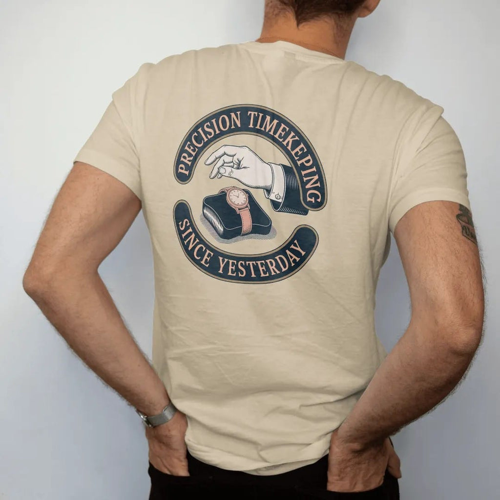 Man wearing a Sandstone tee, seen from the back: a vintage ad of a hand presenting a watch on a velvet cushion with sparkles, under Precision Timekeeping and a Since Yesterday script, as a fine engraving in navy and antique brass.