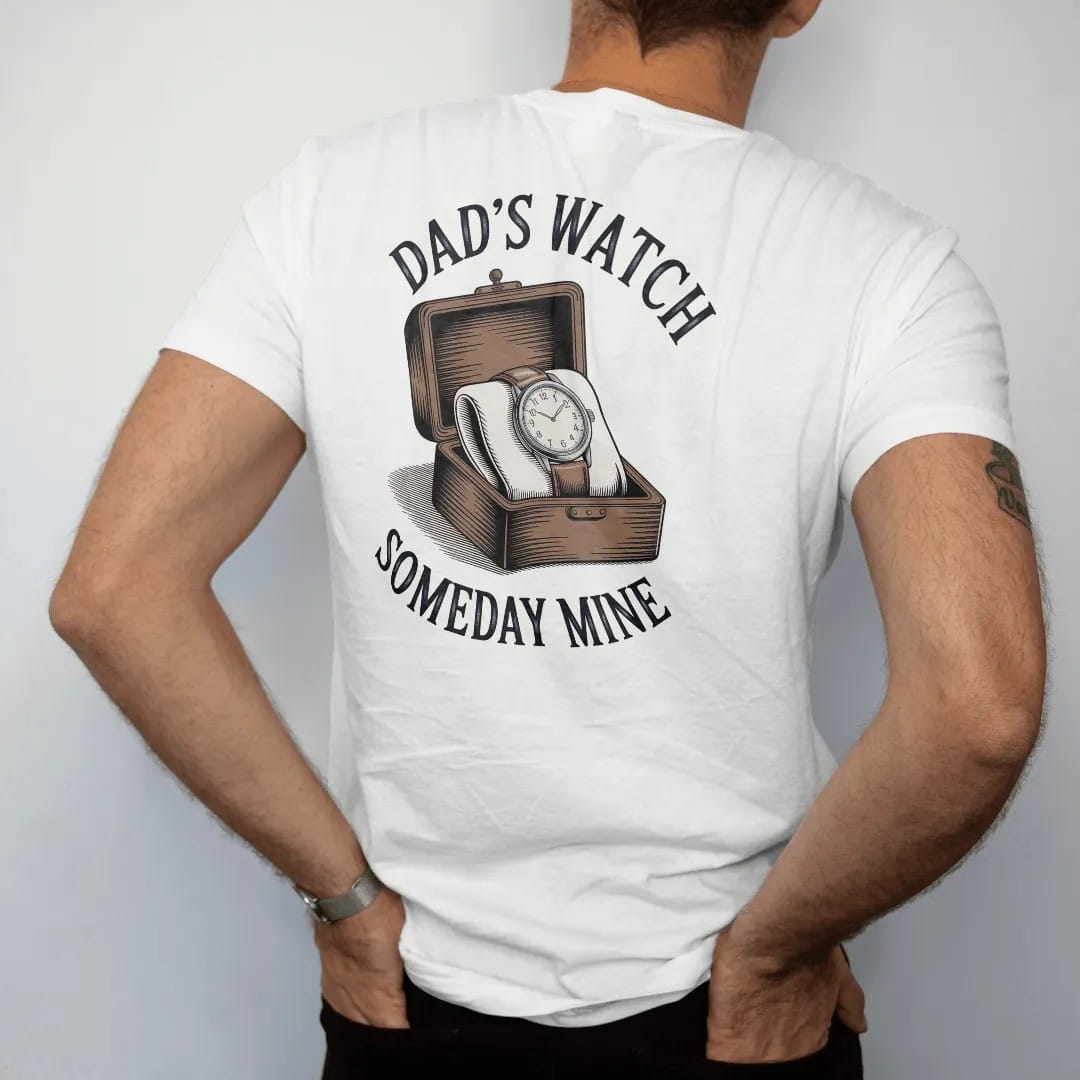 Man wearing a White tee, seen from the back: a worn vintage watch on a leather strap in a small wooden box, under Dad's Watch and the script Someday Mine, as a fine engraving in navy and antique brass.