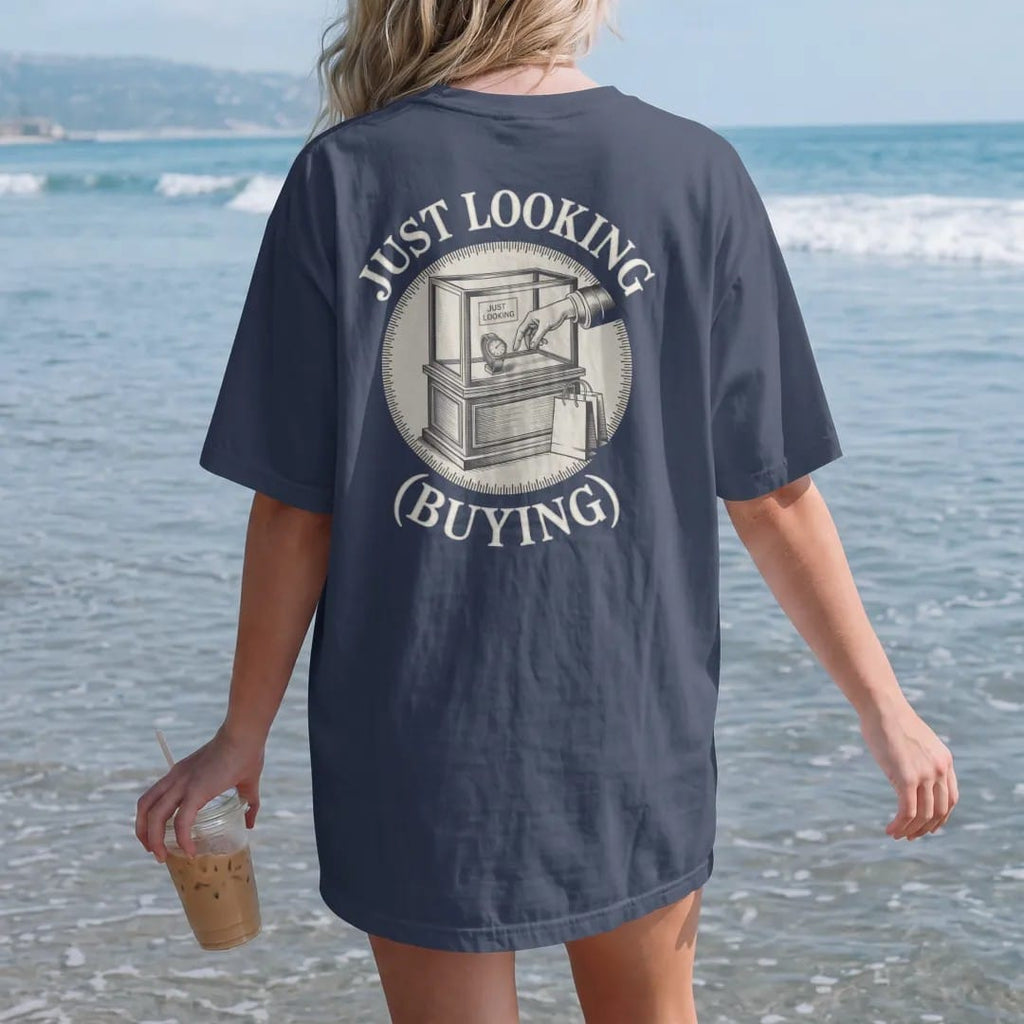 Woman on the beach in a Navy tee, back view: a boutique display case with a hand reaching for a watch and a small shopping bag, under Just Looking and a small (Buying), as a fine engraving in antique gold and cream.