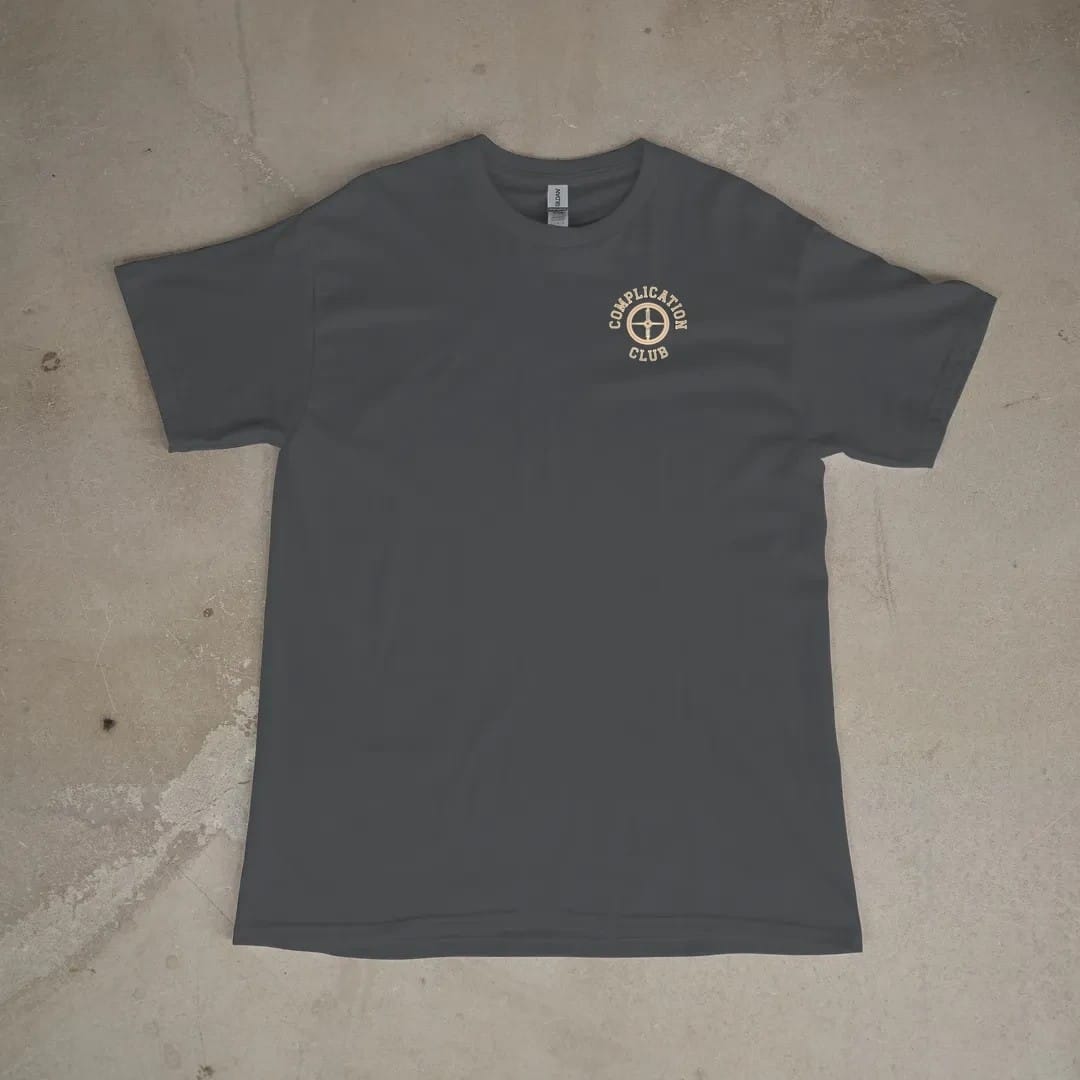 Front of a Graphite tee laid flat, with the small Complication Club logo on the left chest.