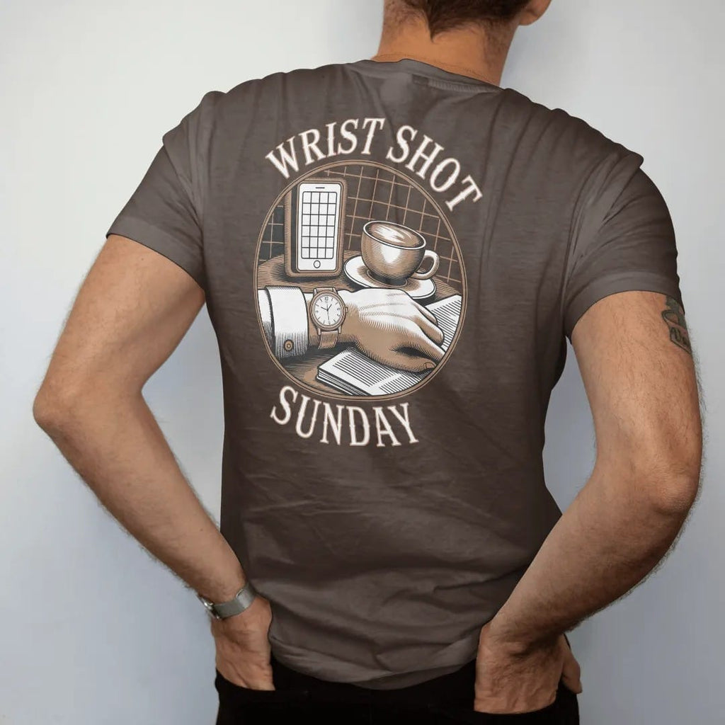 Man wearing a Espresso tee, seen from the back: a wrist with a watch on a café table beside a cappuccino and newspaper inside a camera grid, under Wrist Shot and Sunday, as a fine engraving in antique gold and cream.