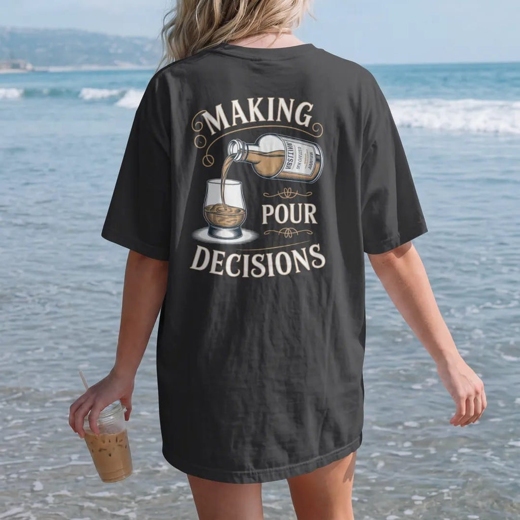 Woman on the beach in a Black tee, back view: an engraved bottle pouring into a glencairn glass, with "MAKING" and "POUR DECISIONS" in flowing copperplate script and bold Didone capitals, printed as a fine engraving in antique gold and warm cream.