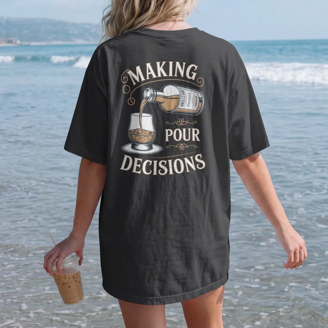 Woman on the beach in a Black tee, back view: an engraved bottle pouring into a glencairn glass, with "MAKING" and "POUR DECISIONS" in flowing copperplate script and bold Didone capitals, printed as a fine engraving in antique gold and warm cream.
