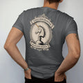 Man wearing a Graphite tee, seen from the back: an engraved unicorn head emerging from a whiskey bottle, with "UNICORN HUNTER" and "ALLOCATED SEASON" in ornate engraved Didone capitals, printed as a fine engraving in antique gold and warm cream.