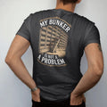Man wearing a Black tee, seen from the back: a wall of shelves packed with whiskey bottles and a library ladder, with "MY BUNKER" and "IS NOT A PROBLEM", printed as a fine engraving in antique gold and warm cream.