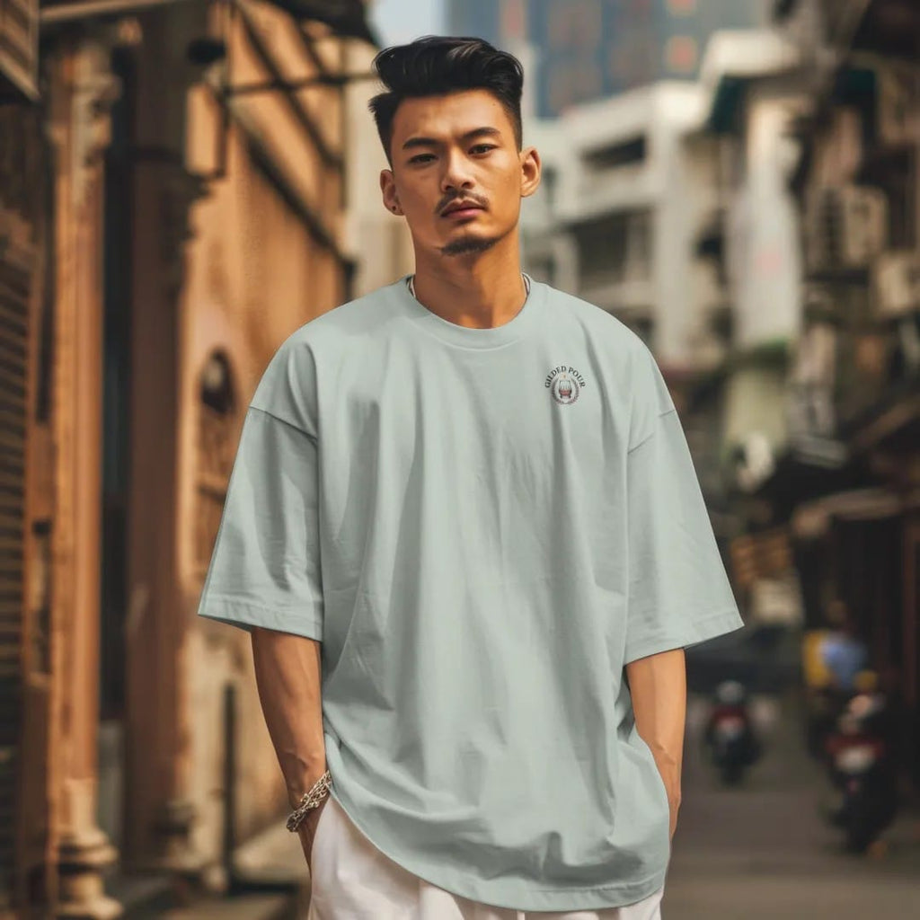 Man in a Bay tee on a city street, with the small Gilded Pour logo on the left chest.