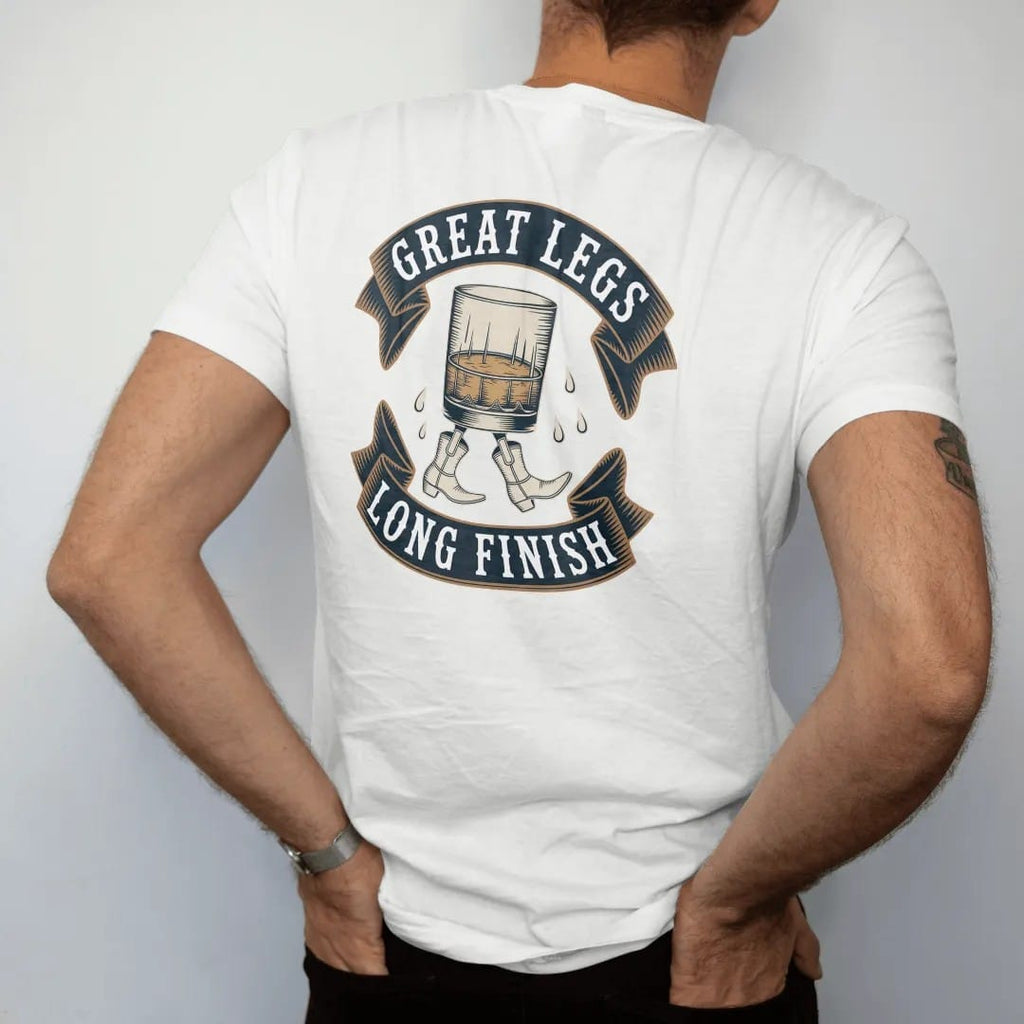 Man wearing a White tee, seen from the back: a whiskey glass walking on cartoon legs in cowboy boots, with "GREAT LEGS" and "LONG FINISH" in playful Victorian display capitals, printed as a fine engraving in antique gold and warm cream.
