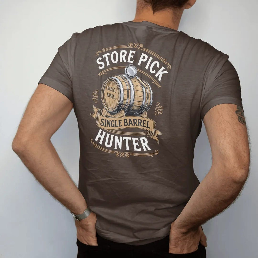 Man wearing a Espresso tee, seen from the back: an engraved barrel with a chalk number and a magnifying glass, with "STORE PICK" and "SINGLE BARREL HUNTER", printed as a fine engraving in antique gold and warm cream.