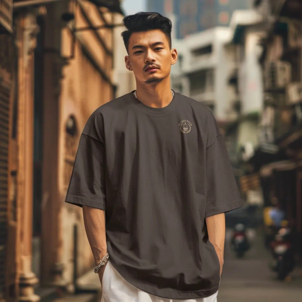 Man in a Espresso tee on a city street, with the small Gilded Pour logo on the left chest.