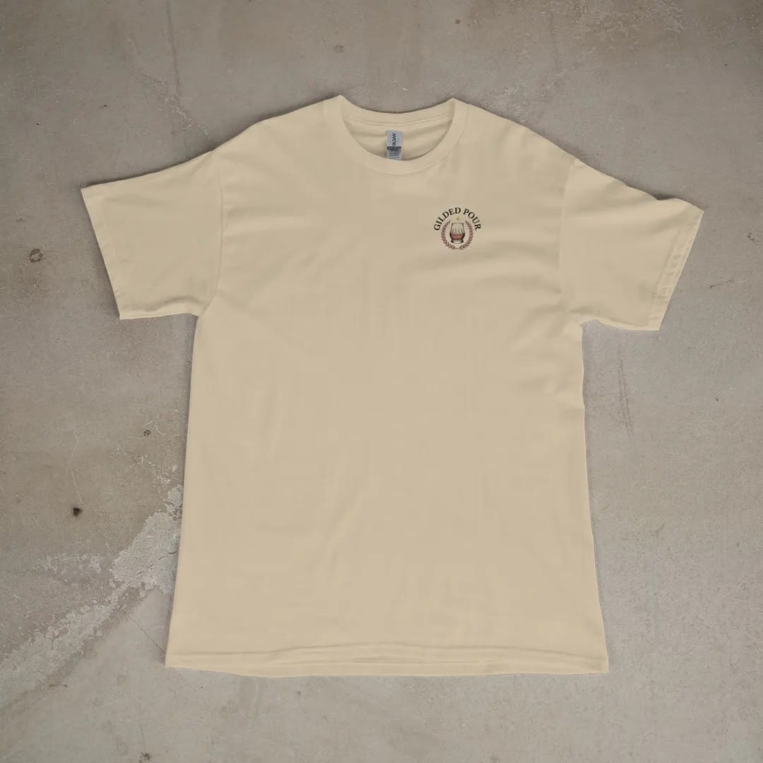 Front of a Sandstone tee laid flat, with the small Gilded Pour logo on the left chest.