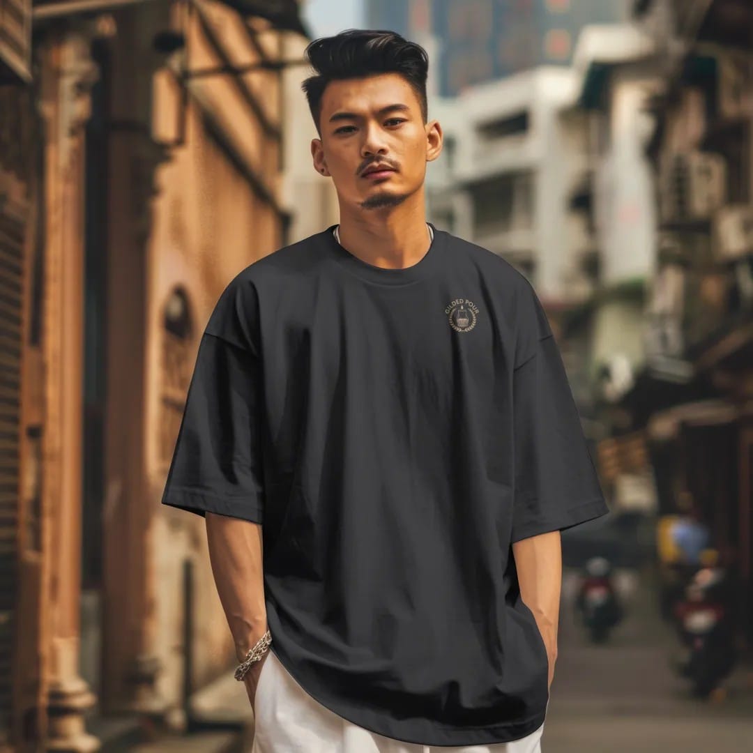 Man in a Black tee on a city street, with the small Gilded Pour logo on the left chest.