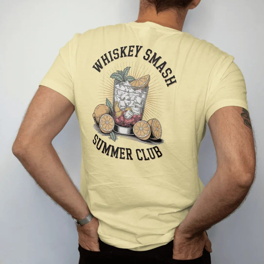 Man wearing a Butter tee, seen from the back: a whiskey smash with lemons and mint over sunburst rays, with "WHISKEY SMASH" and "SUMMER CLUB", printed as a fine engraving in oxblood, charred oak brown and antique gold.