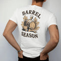 Man wearing a White tee, seen from the back: an oak barrel with autumn leaves, acorns and a pumpkin, with "BARREL SEASON" in warm Victorian serif capitals, printed as a fine engraving in antique gold and warm cream.