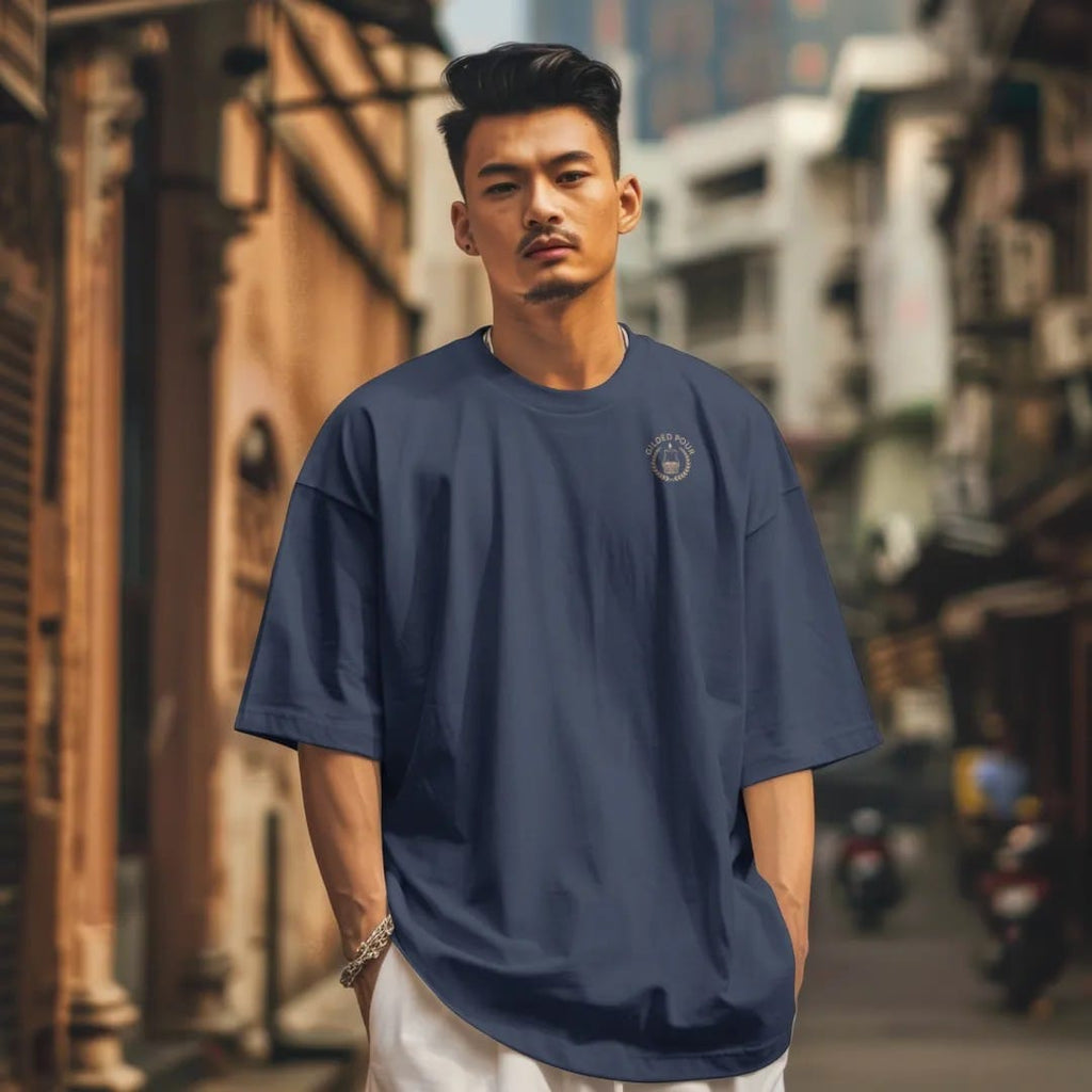 Man in a Navy tee on a city street, with the small Gilded Pour logo on the left chest.