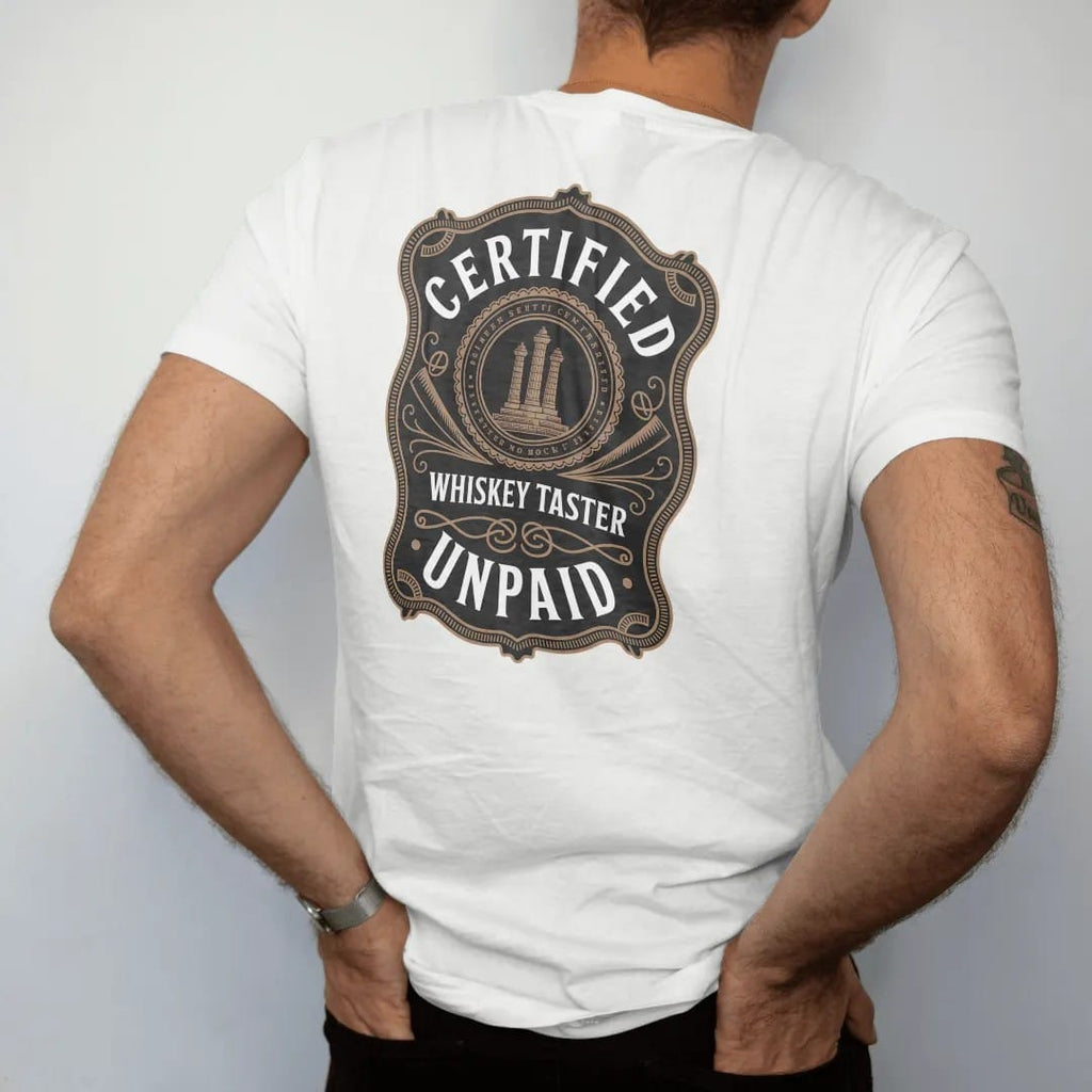 Man wearing a White tee, seen from the back: a diploma-style seal with a glencairn glass and ribbon tails, with "CERTIFIED", "WHISKEY TASTER" and "UNPAID", printed as a fine engraving in antique gold and warm cream.