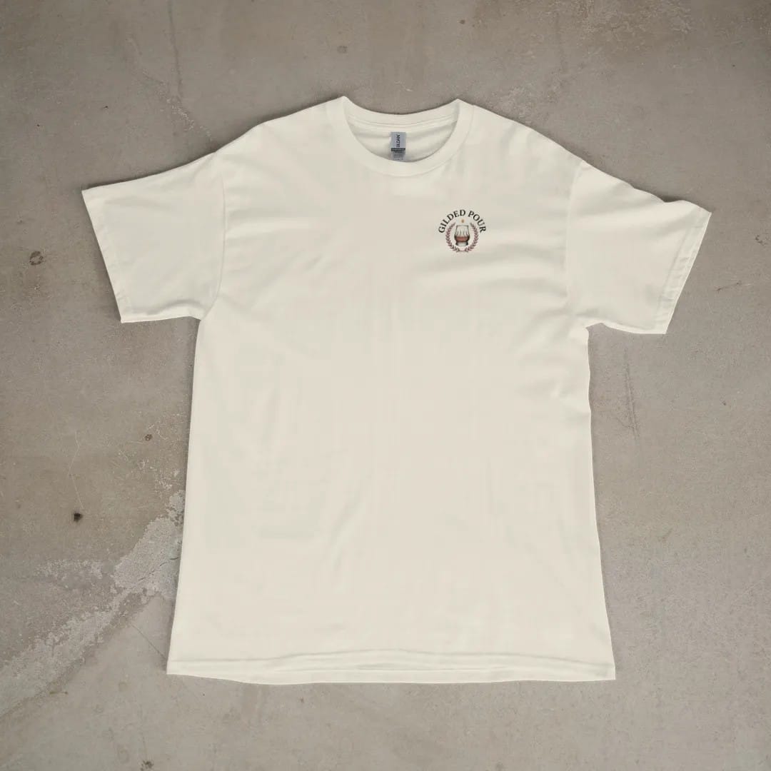 Front of a Ivory tee laid flat, with the small Gilded Pour logo on the left chest.