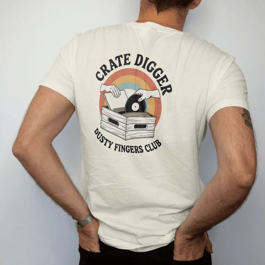 Man wearing a Ivory tee, seen from the back: two hands flipping through a wooden crate of record sleeves, with "CRATE DIGGER" and "DUSTY FINGERS CLUB" in chunky 70s lettering and small 70s caps, printed in faded, cracked cream, mustard, burnt…