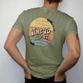 Man wearing a Moss tee, seen from the back: a record flipping mid-air with motion arrows, with "TIME TO" and "FLIP IT" in chunky 70s lettering and small 70s caps, printed in faded, cracked cream, mustard, burnt orange and faded teal over faded…