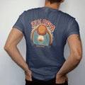 Man wearing a Navy tee, seen from the back: a turntable speed knob with a sun setting into a spinning record, with "33⅓ RPM" and "SLOW DOWN" in chunky 70s lettering and small 70s caps, printed in faded, cracked cream, mustard, burnt orange and…
